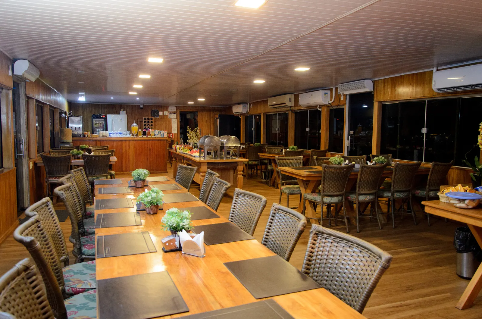 Refeitório da Balsa Transpantanal, com mesas de madeira postas e o buffet montado