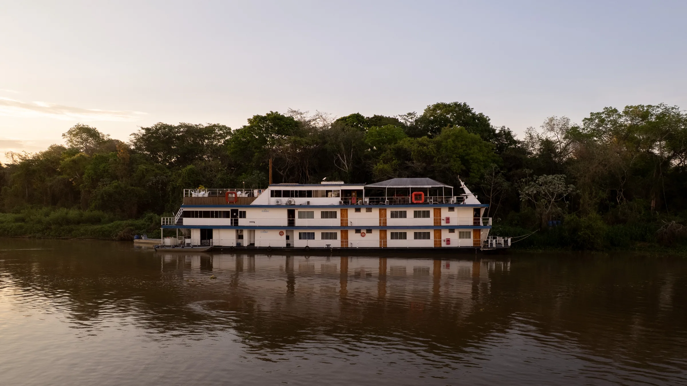 Barco-hotel da Transpantanal ancorado no rio, visto do alto ao entardecer