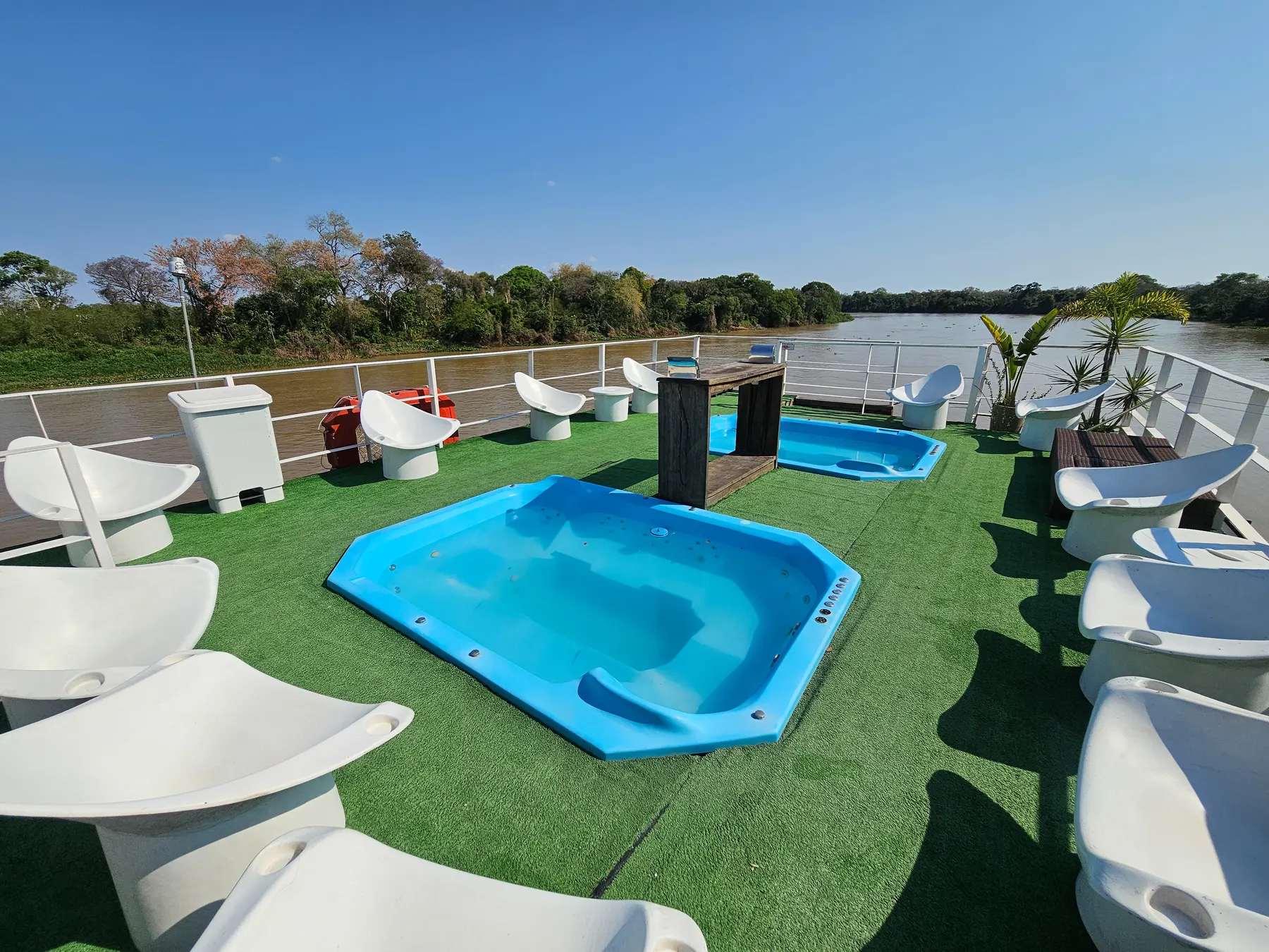 Deck superior do Barco Panorâmico, com piscina e espreguiçadeiras diante do rio